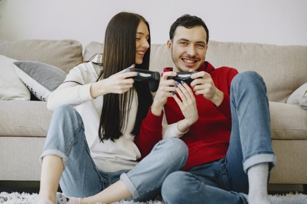 Giocare ai videogiochi jpg. uomo e donna giocano ai videogames seduti sul divano e sorridono