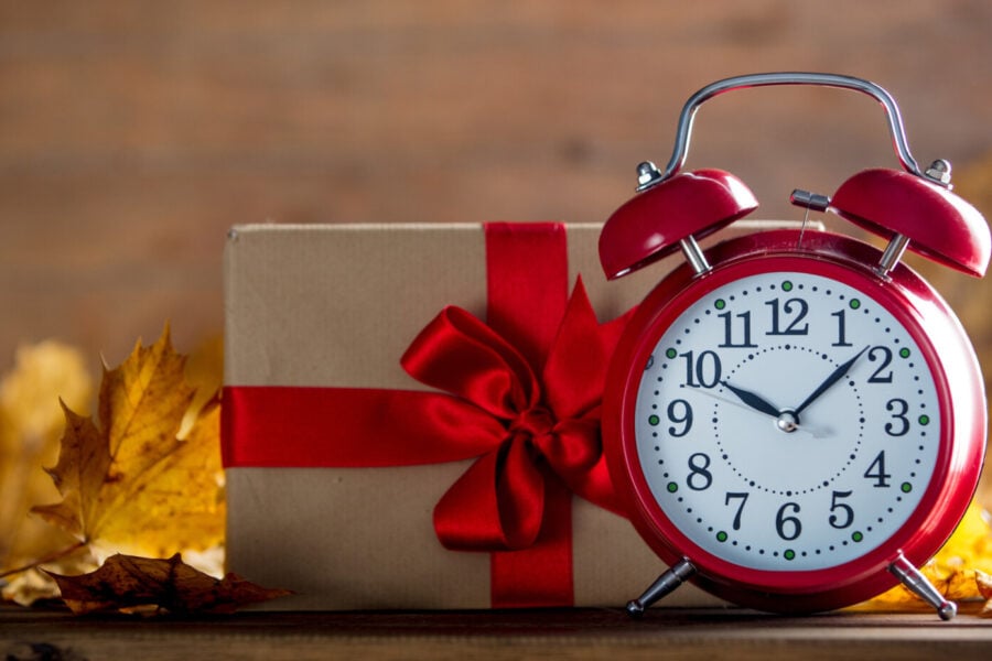 Economia del dono. L'immagine raffigura una sveglia accanto a un pacco regalo.