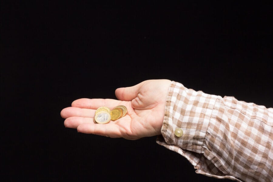 Costa poco: in primo piano una mano con delle monetine.