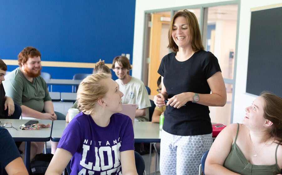 Maturità 2025, voto in condotta. Un'insegnante tra i banchi di una classe sorridente