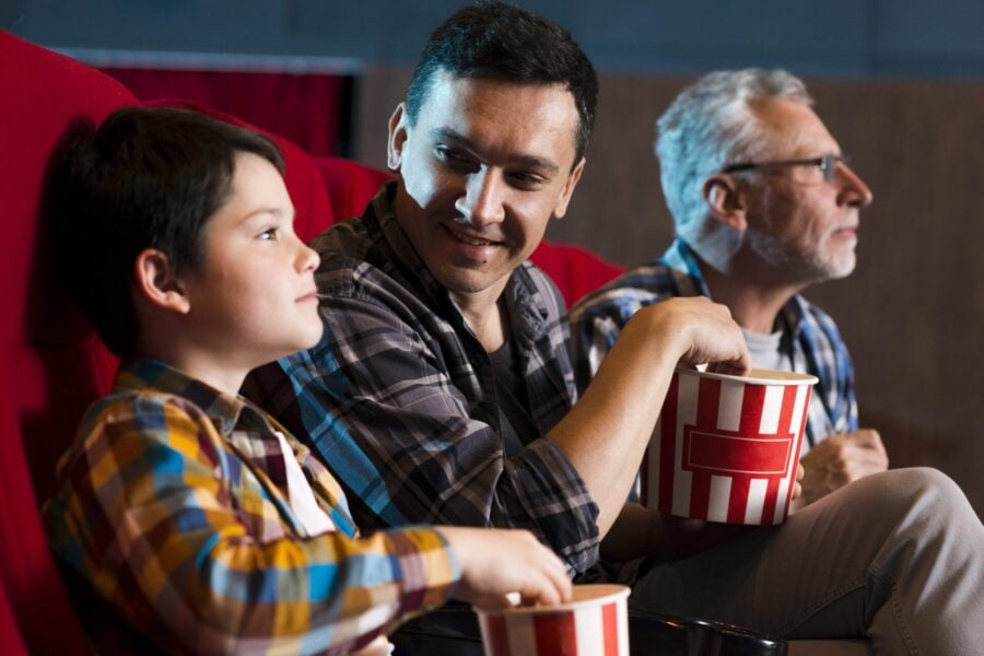 film al cinema: nonno, padre e figlio siedono al cinema guardando i fantastici 4
