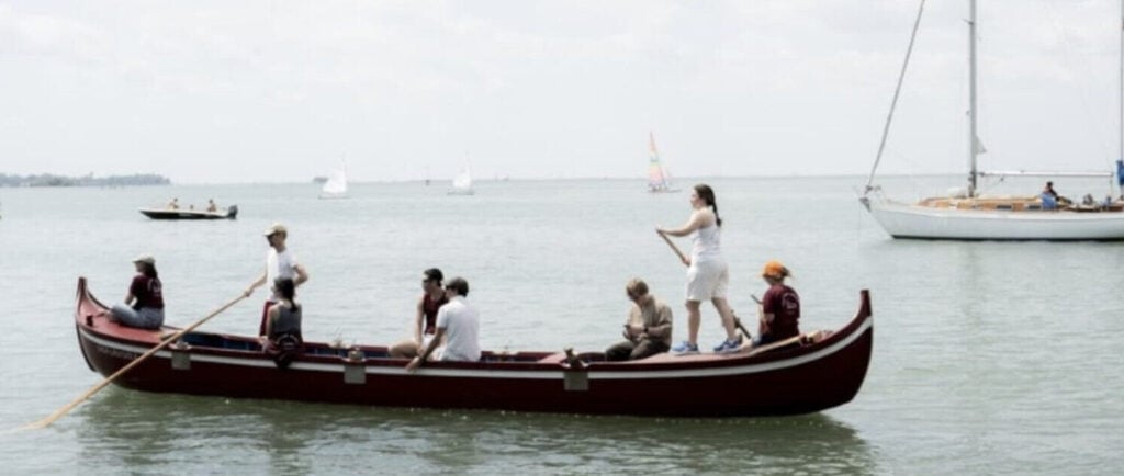 alcune persone si dirigono verso l'isola con la barca a remi, perché attualmente è l'unico modo per arrivarci 