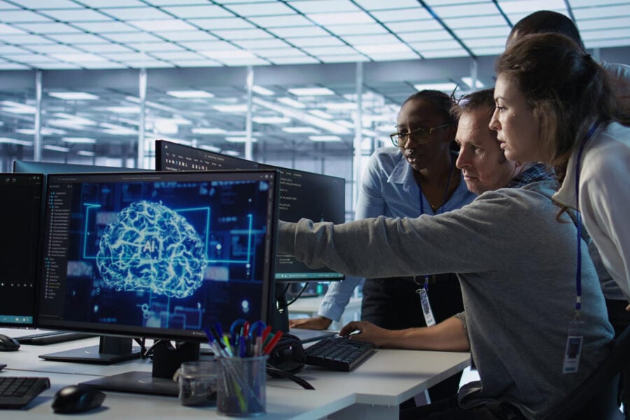 Un team di professionisti osserva e analizza insieme modelli di intelligenza artificiale in un moderno ambiente di lavoro tecnologico.