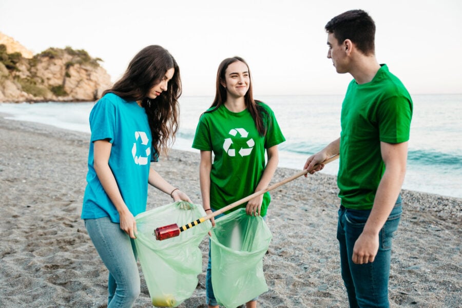 Volontari impegnati nella raccolta dei rifiuti su una spiaggia durante un’iniziativa plastic free.