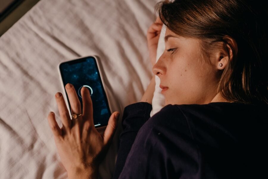 Donna mentre utilizza lo smartphone prima di dormire