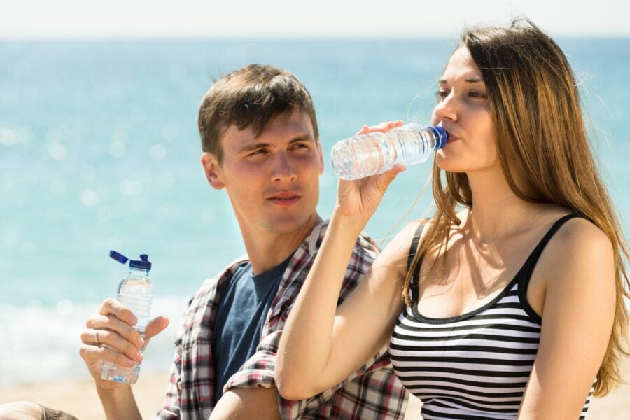 bevande estive: giovane coppia beve una bottiglia d'acqua per dissetarsi